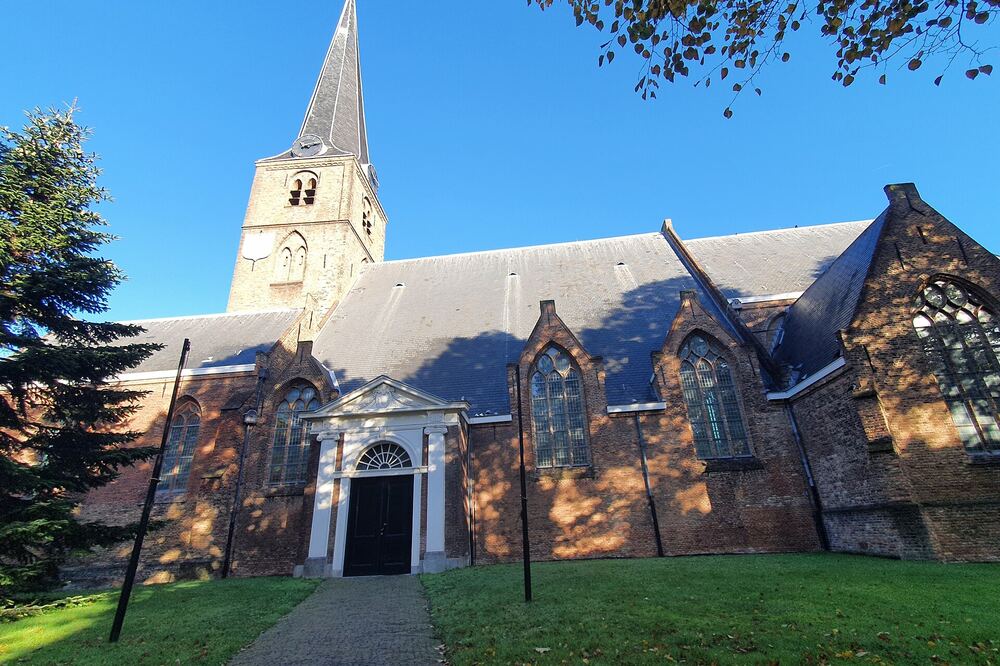 De Oude Kerk in Rijswijk met hoge spits en monumentale ingang onder een blauwe hemel